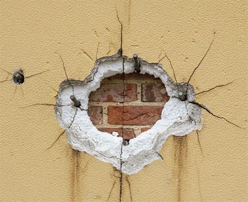 Detailní pohled na odhalenou izolaci a kotvení ocelové konstrukce do zdiva skrz zateplenou fasádu.