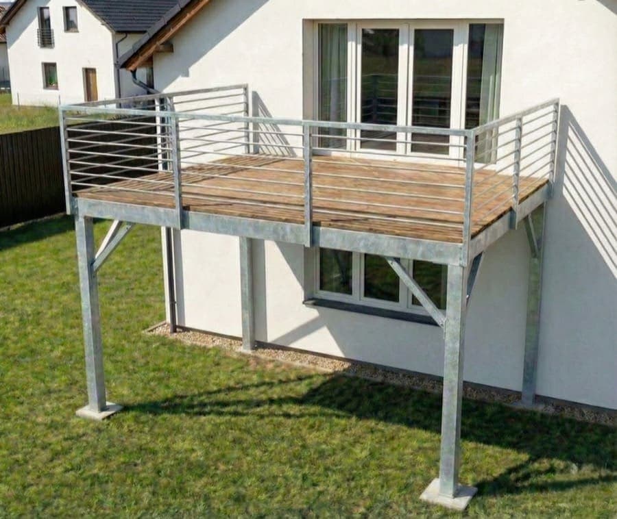 Ocelová terasa na sloupech se zábradlím | KOVOSET Vyvýšená ocelová terasa na sloupech s dřevěnou podlahou a zinkovaným zábradlím u rodinného domu.