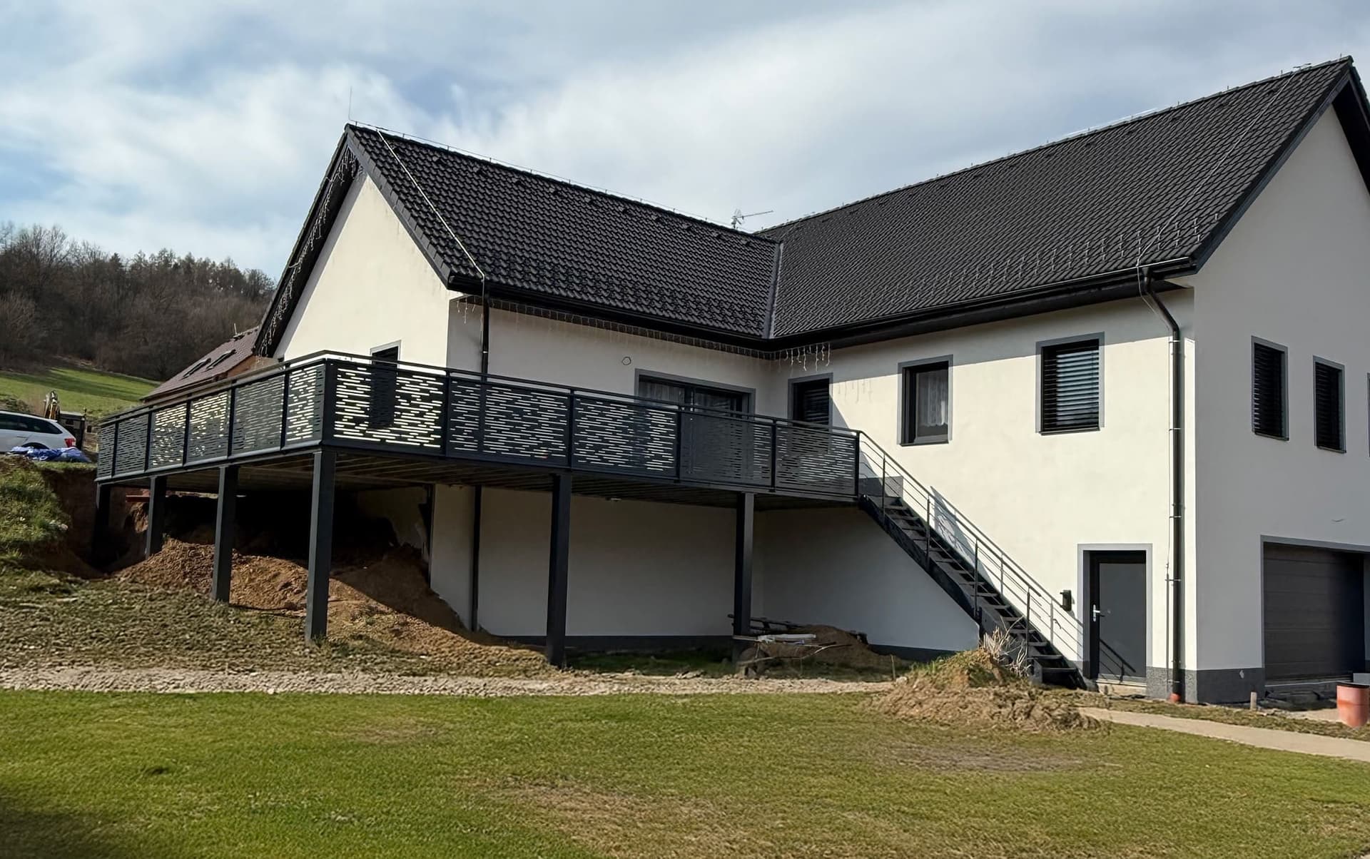 Schodiště Moderní ocelová konstrukce rohové terasy s venkovním schodištěm a dekorativním plechovým zábradlím u rodinného domu.